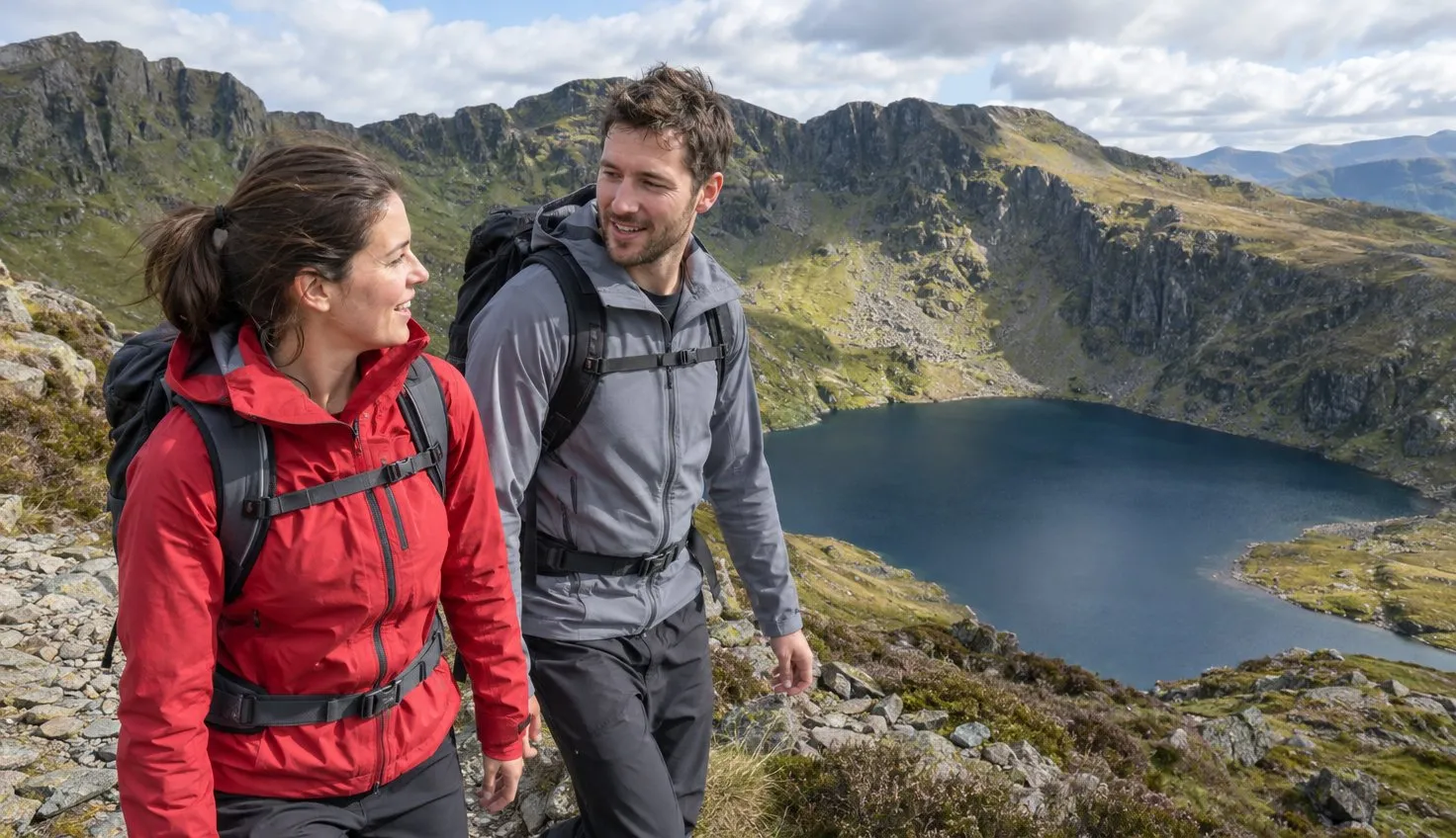 Two walkers on the rim above Llyn Cau below the crags of Cadair Idris