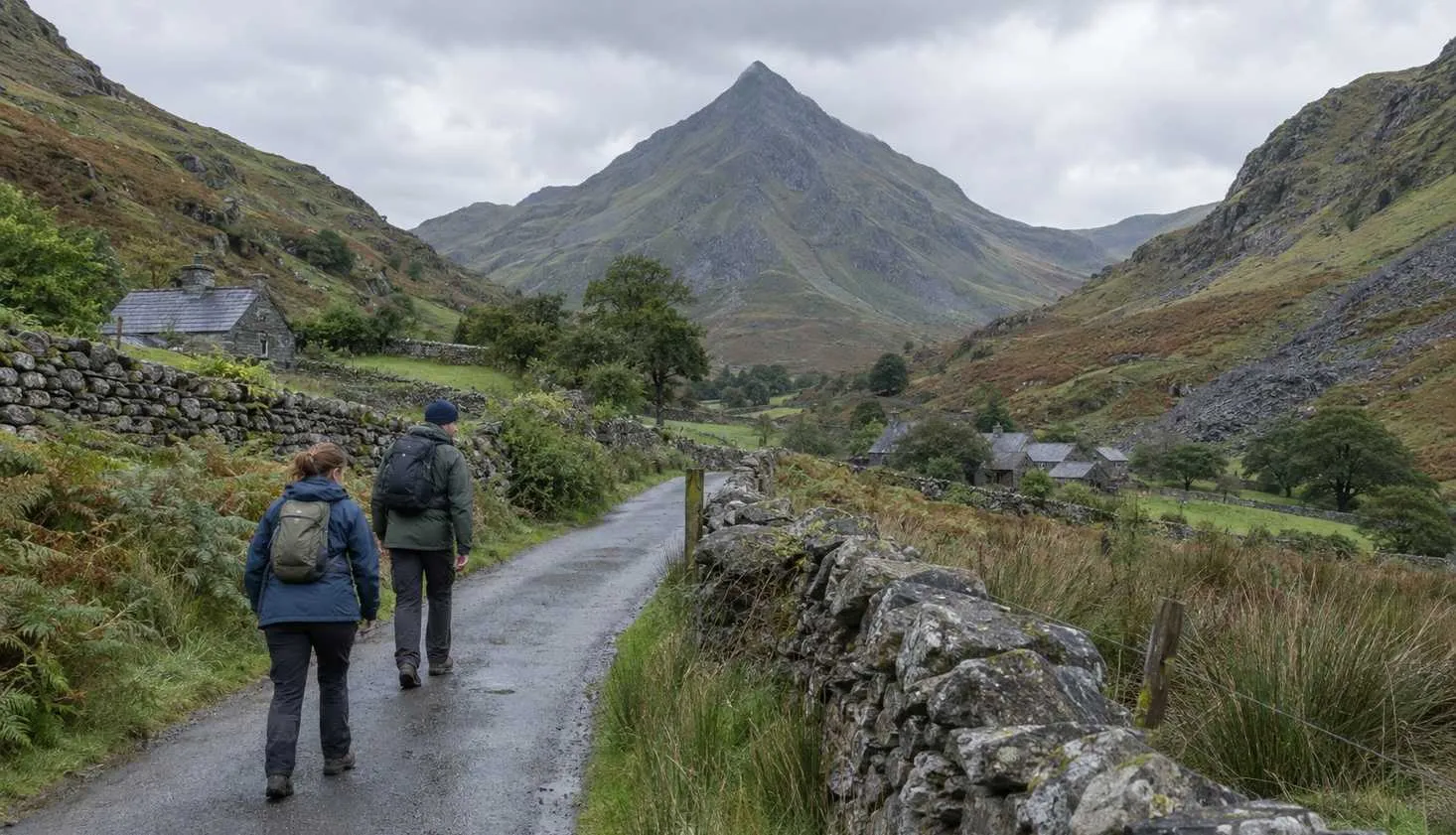 Two walkers on the lane out of Croesor with the pointed profile of Cnicht at the head of the valley.