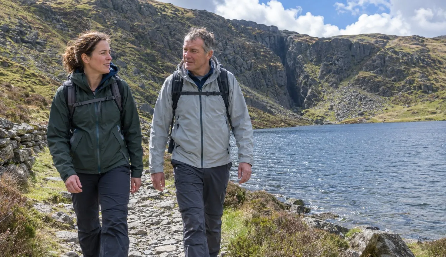 Two walkers on the path round Llyn Idwal with the Devil's Kitchen cliffs behind