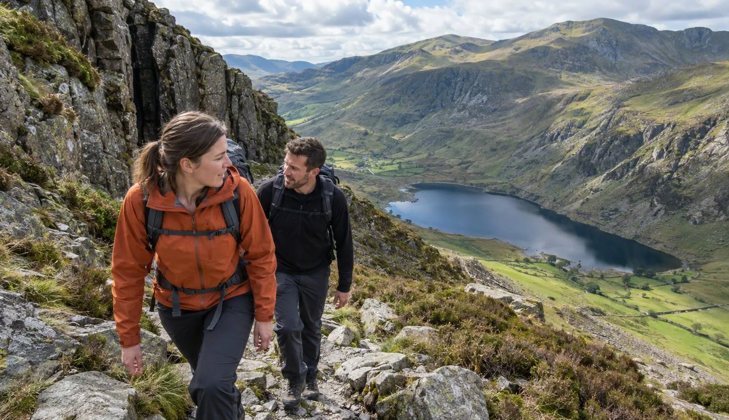 Two walkers climbing the boulder path by the Devil's Kitchen, Llyn Idwal far below