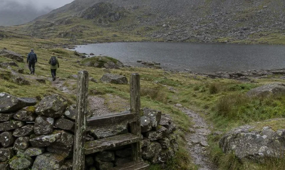 The stile at the top of the Devil's Kitchen path, with Llyn y Cwn beyond and the scree slope to Glyder Fawr rising into cloud.