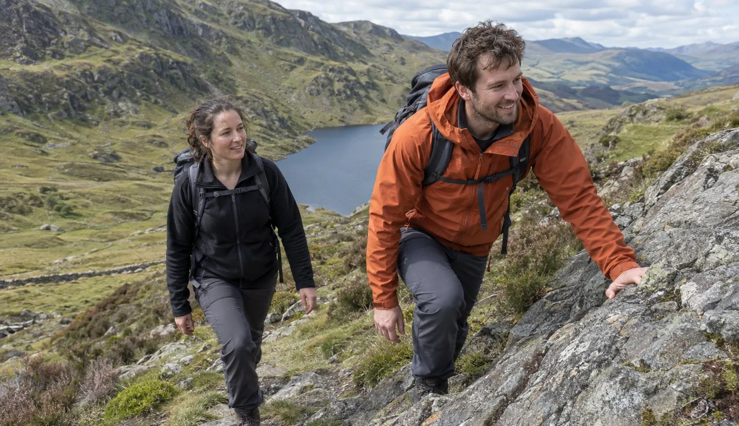 Two walkers on Moel Siabod's Daear Ddu ridge, one on the rock and one on the path beside it