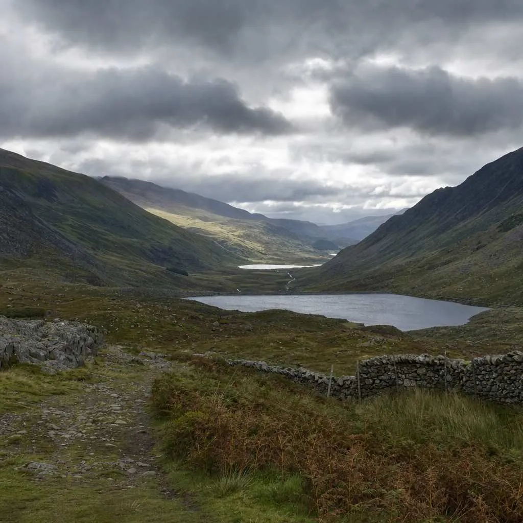 a wide Welsh valley under a broken threatening sky