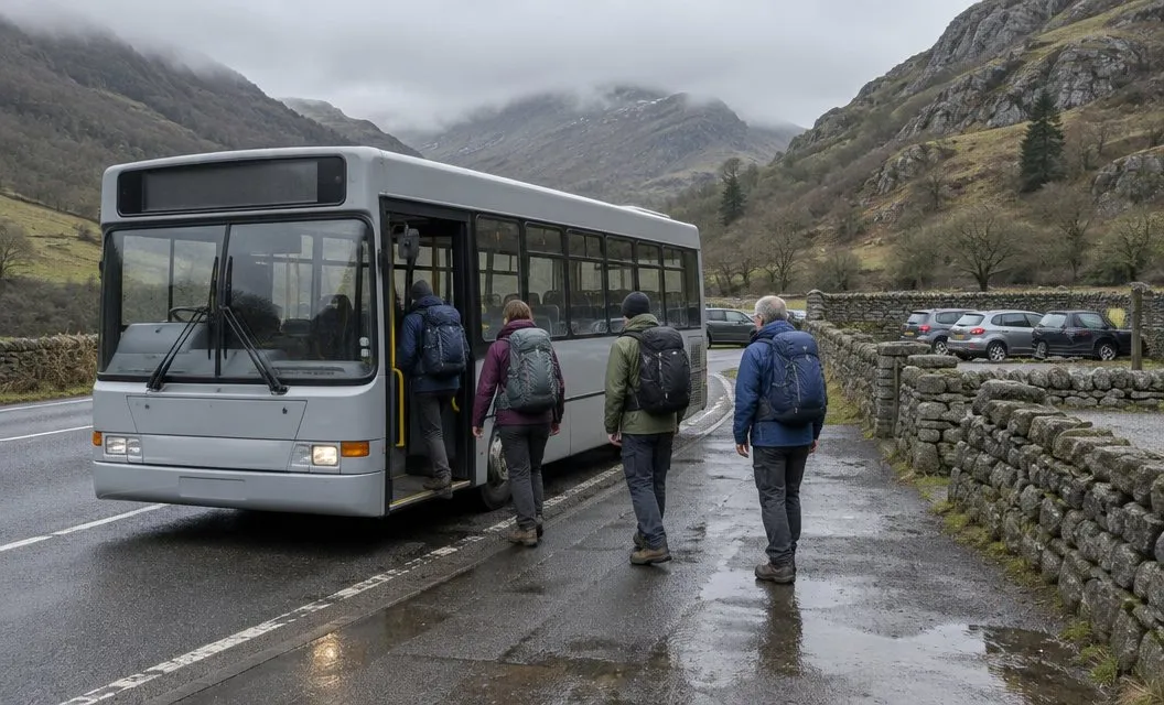 Walkers with rucksacks climbing aboard a small bus at a stop on a mountain pass, cloud on the hills behind.