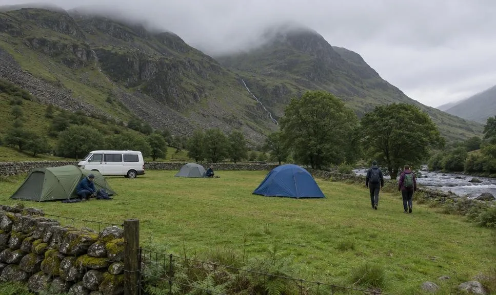 Small tents and a campervan on a valley campsite with mountains in cloud behind.