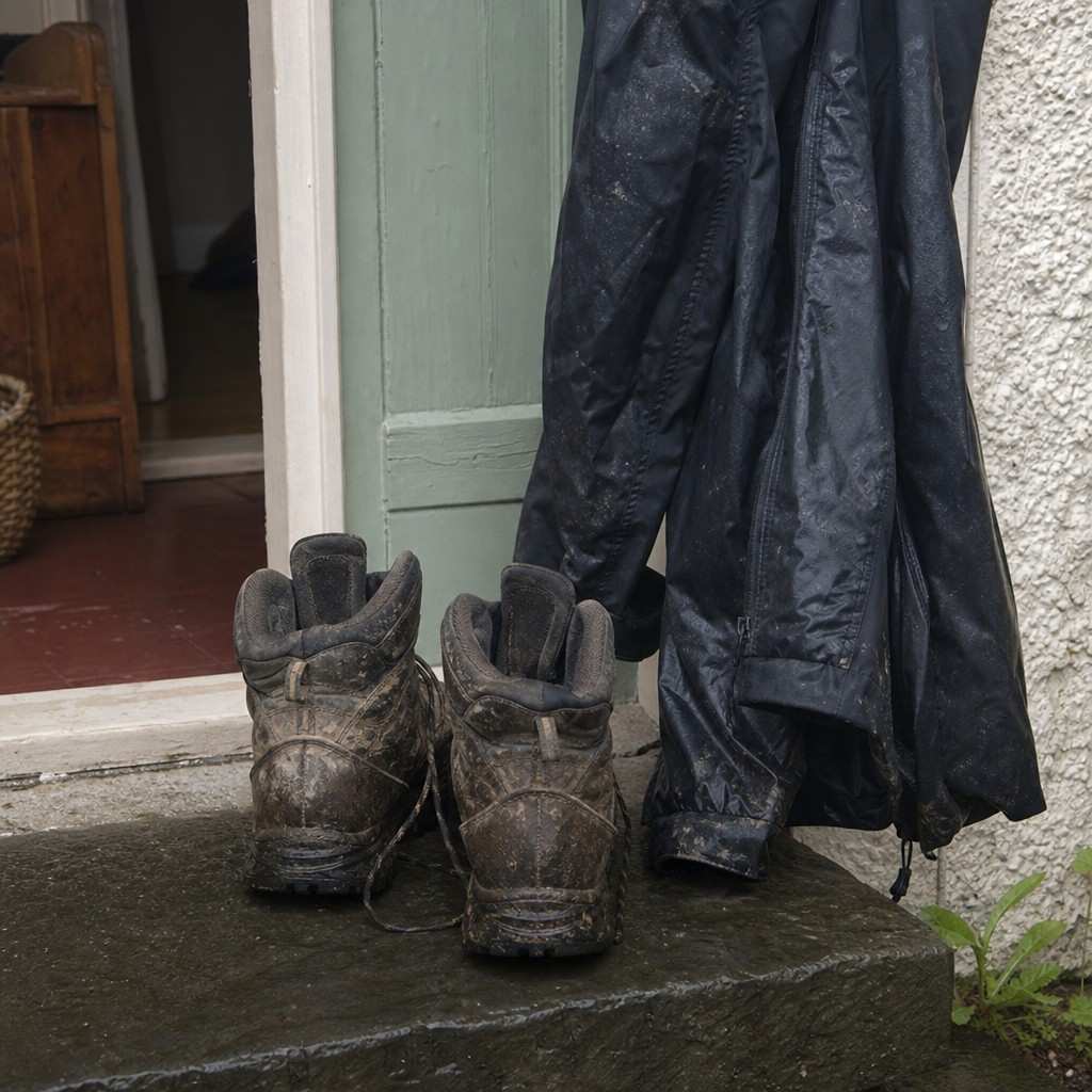 muddy boots and a waterproof drying by a door
