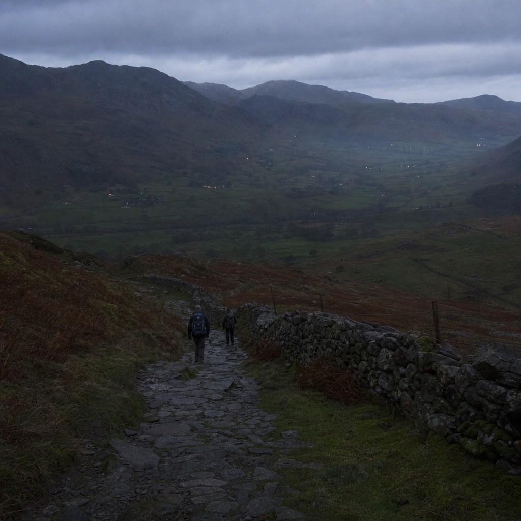 Walkers on the lower path as daylight fades over the valley