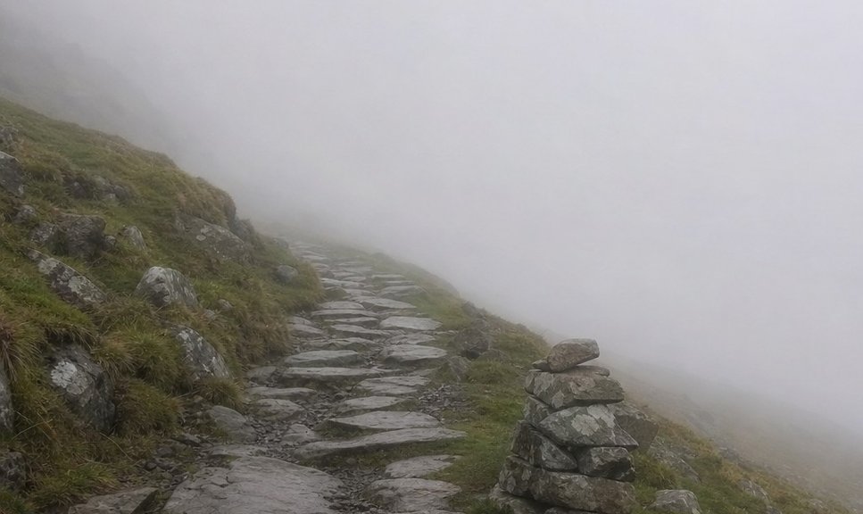 A stony mountain path disappearing into low cloud in Snowdonia