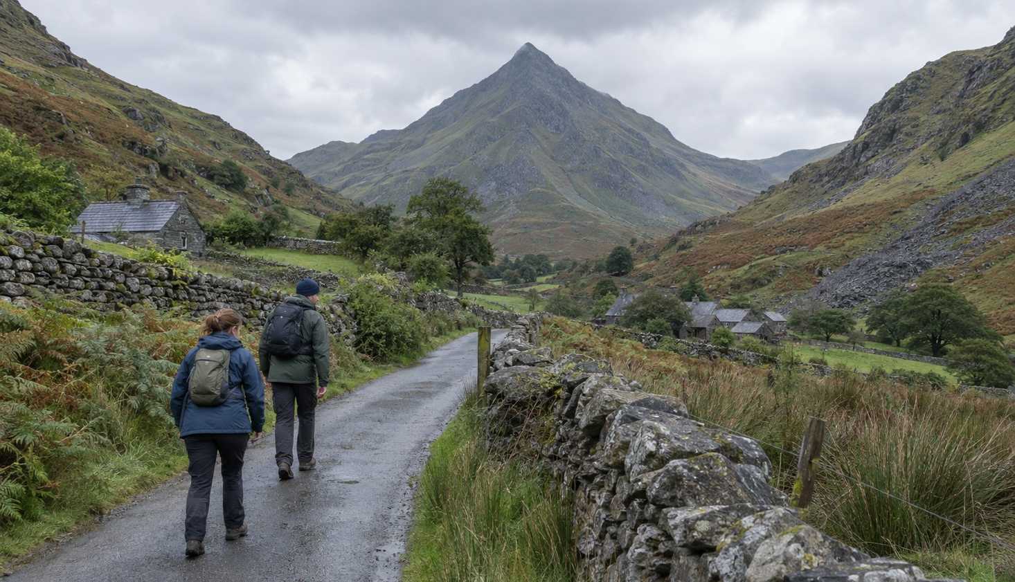 Two walkers on the lane out of Croesor with the pointed profile of Cnicht at the head of the valley.